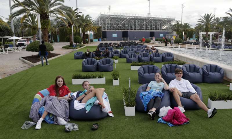 In this Thursday, June 18, 2020 file photo, people sit outdoors to watch a movie as part of a program offered by the Miami Dolphins at Hard Rock Stadium during the coronavirus pandemic in Miami Gardens, Fla. Elected officials such as Florida's governor have argued against reimposing restrictions, saying many of the newly infected are young and otherwise healthy. But younger people, too, face the possibility of severe infection and death. And authorities worry that older, more vulnerable people could be next. (AP Photo/Lynne Sladky) Virus cases surging among the young, endangering the elderly