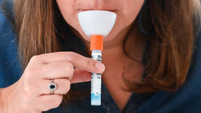 A woman spits into a saliva test kit