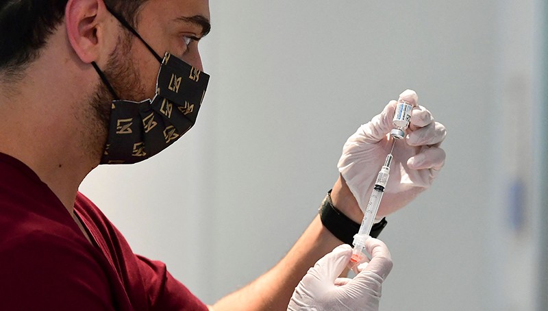 A health-care worker prepares a vaccine injection.