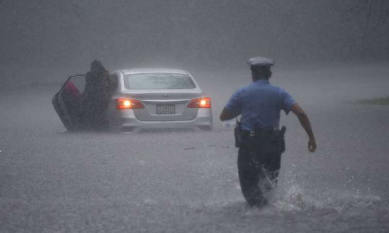 A Philadelphia police officer rushes to help a stranded motorist during Tropical Storm Isaias, Tuesday, Aug. 4, 2020, in Philadelphia. The storm spawned tornadoes and dumped rain during an inland march up the U.S. East Coast after making landfall as a hurricane along the North Carolina coast. (AP Photo/Matt Slocum) Tropic storm Isaias whips up eastern US, killing at least 6
