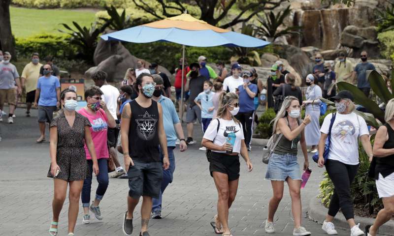 Guests wearing masks stroll through SeaWorld as it reopened with new safety measures in place Thursday, June 11, 2020, in Orlando, Fla. The park had been closed since mid-March to stop the spread of the new coronavirus. (AP Photo/John Raoux) Alarming rise in virus cases as states roll back lockdowns