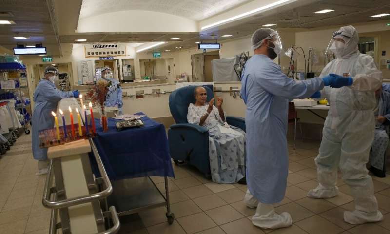 Staff and patients celebrate after lighting Hanukkah candles at the COVID-19 isolation ward of Tel Aviv Sourasky Medical Center Staff and patients celebrate after lighting Hanukkah candles at the COVID-19 isolation ward of Tel Aviv Sourasky Medical Center