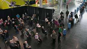 People wait in line to receive a COVID-19 vaccine at National Health Service