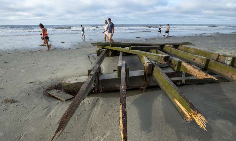 People walk Cherry Grove Point at dawn looking at debris scattered by Hurricane Isaias in North Myrtle Beach, S.C. Tuesday, Aug. 4, 2020. (Jason Lee/The Sun News via AP) Tropic storm Isaias whips up eastern US, killing at least 6