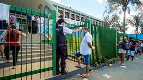People line up to have their temperature taken before entering a building