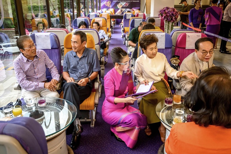 A waitress wearing a face shield serves customers in an aeroplane-themed restaurant in Thailand