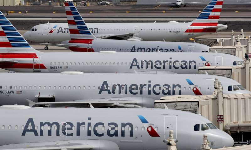 In this March 25, 2020, file photo, American Airlines jets sit idly at their gates as a jet arrives at Sky Harbor International Airport in Phoenix. American Airlines is telling 25,000 workers that they could lose their jobs in October because of the sharp drop in air travel during the virus pandemic. The airline said Wednesday, July 15, it was starting new offers of buyouts and partially paid leave, which it hopes will reduce the number of furloughs. (AP Photo/Matt York, File) American, pilots agree on steps aimed at reducing job cuts