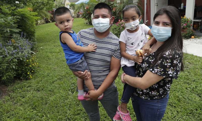In this Sunday, June 7, 2020, photo, Elbin Sales, second from left, poses for a photograph with his wife, Yecenia Solorzano, right, and children Jordi Sales, left, and Athena Sales, amid the new coronavirus pandemic in Immokalee, Fla. Sales, who works as a landscaper, tested positive for COVID-19 and is quarantined at home with his family. Even as the pace of new cases has moderated in the state of Florida, this poor farmworking town in rural Florida is in the throes of an outbreak. (AP Photo/Lynne Sladky) Florida migrant towns become coronavirus hot spots in US