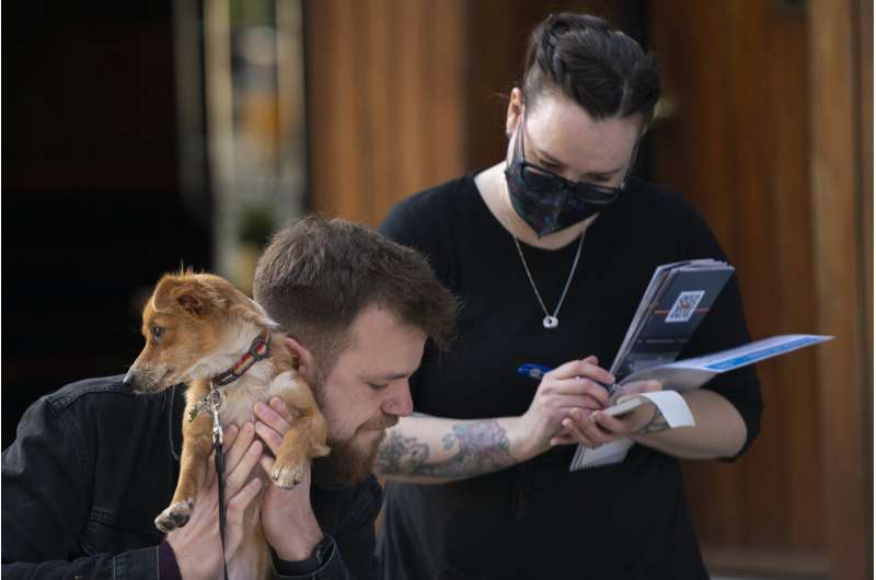 A customer and his dog orders outside a restaurant in Liverpool, England, Monday, April 12, 2021. Millions of people in England will get their first chance in months for haircuts, casual shopping and restaurant meals on Monday, as the government takes the next step on its lockdown-lifting road map. (AP Photo Jon Super) UK hits vaccine target; Johnson warns of more virus deaths