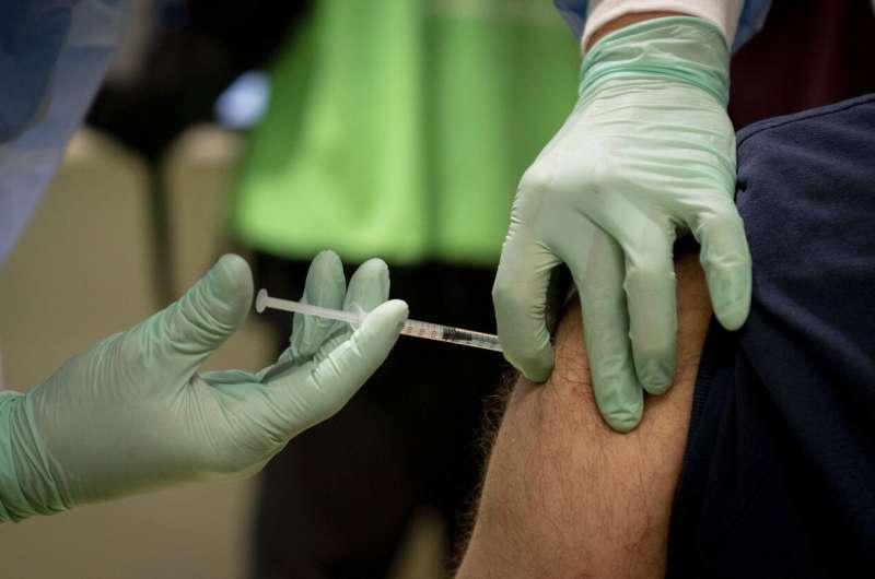 A doctor vaccinates a caregiver at the fourth vaccination center in Berlin, located in Terminal C of the former Tegel Airport, Germany, Wednesday, Feb.10, 2021. Here, at the beginning, mainly nurses and medical staff are vaccinated against the coronavirus. (Nietfeld/dpa via AP) Merkel says German vaccine centers will be full by April