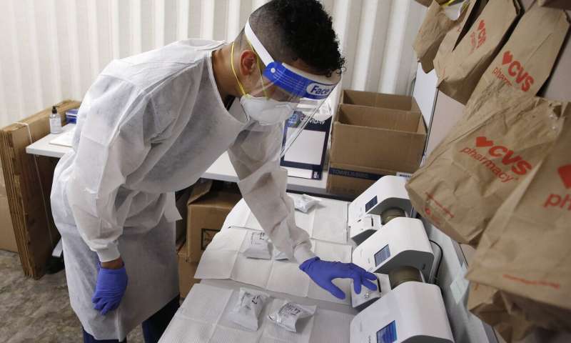 Berto Cortez, a CVS pharmacy technician, shows how COVID-19 tests are processed in a testing area set up by CVS at St. Vincent de Paul medical clinic, Monday, June 15, 2020, in Phoenix. The Arizona Department of Health Services posted on its website Monday another 1,104 cases of COVID-19 and eight additional deaths, bringing the statewide total number of coronavirus cases to 36,705 and related deaths to 1,194. (AP Photo/Ross D. Franklin) Rise in infections shows need for vigilance as world reopens