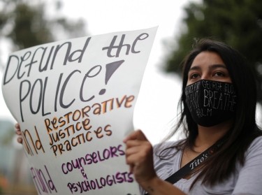 A woman holds a placard as people protest outside Los Angeles Unified School District headquarters to demand that the Board of Education defunds school police in Los Angeles, California, June 23, 2020, photo  by Lucy Nicholson/Reuters