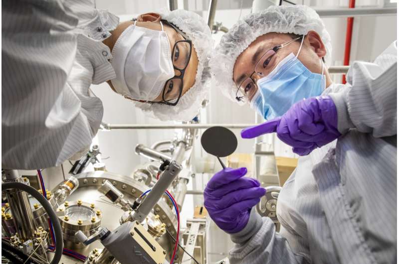 Postdoctoral researchers Ding Wang (left) and Ping Wang (right) check the surface of a single-crystalline ferroelectric ScAlN wafer grown utilizing molecular beam epitaxy. Credit: Robert Coelius Dawn of nitride ferroelectric semiconductors for next-generation electronics