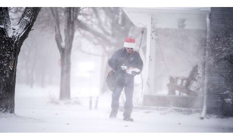 Mail carrier Dennis Niles braves the blowing snow as blizzard like conditions hit Osseo and the Twins Cites on Wednesday, Dec. 23, 2020 in Osseo, Minn. (Jerry Holt/Star Tribune via AP) Winter storm in Dakotas, Minnesota make travel frightful