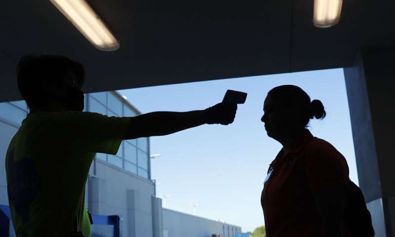 In this May 29, 2020, file photo, amid concerns of the spread of COVID-19, an employee has their temperature checked before starting their shift at the city owned waterpark in Grand Prairie, Texas. Coronavirus cases are rising in nearly half the U.S. states, as states are rolling back lockdowns. (AP Photo/LM Otero, File) Many forces behind alarming rise in virus cases in 21 states