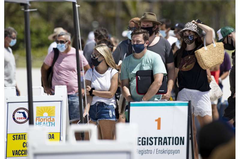 In this May 2, 2021, file photo, people line up to receive a Johnson & Johnson vaccine at the one-time pop-up vaccination site located 16th Street beach on the sand in Miami Beach. Nearly 45% of the nation's adults are fully vaccinated, and over 58% have received at least one dose, according to the Centers for Disease Control and Prevention. (David Santiago/Miami Herald via AP, File) Taming the virus: US deaths hit lowest level in 10 months