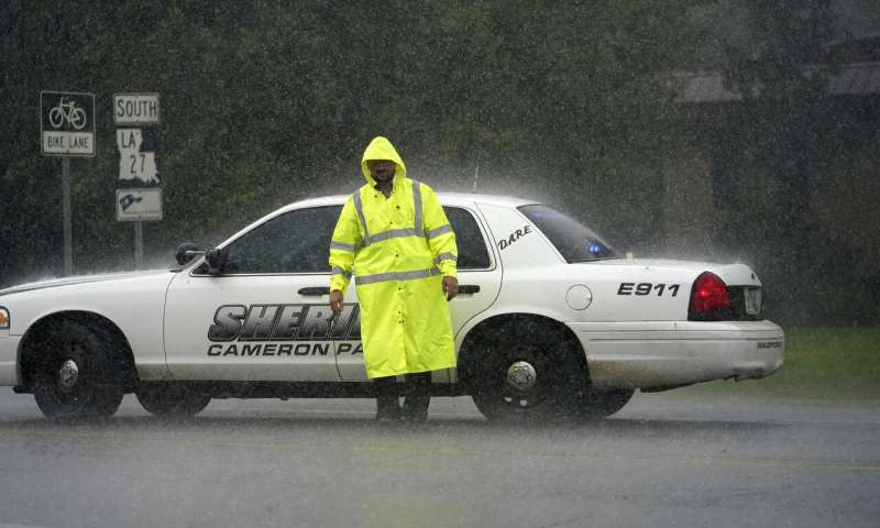 A Cameron Parish Sheriff's deputy mans a roadblock in the rain on LA 27 as residents evacuate Cameron in Lake Charles, La., Wednesday, Aug. 26, 2020, ahead of Hurricane Laura. (AP Photo/Gerald Herbert) Laura strengthens into 'extremely dangerous' Category 4