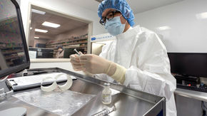 In a clean room, a pharmacist attaches a label to a syringe
