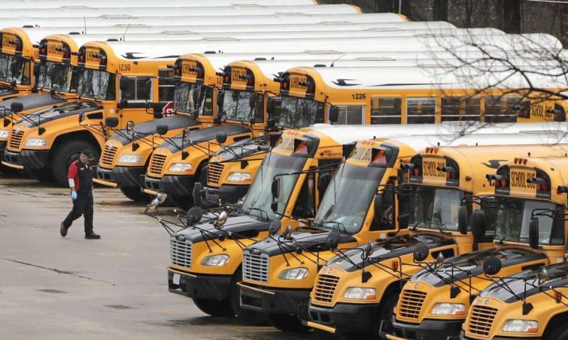 In this April 27, 2020, file photo, a worker passes public school buses parked at a depot in Manchester, N.H. As the Trump administration pushes full steam ahead to force schools to resume in-person education, public health experts warn that a one-size-fits-all reopening could drive infection and death rates even higher. (AP Photo/Charles Krupa, File) Virus spread, not politics should guide schools, doctors say